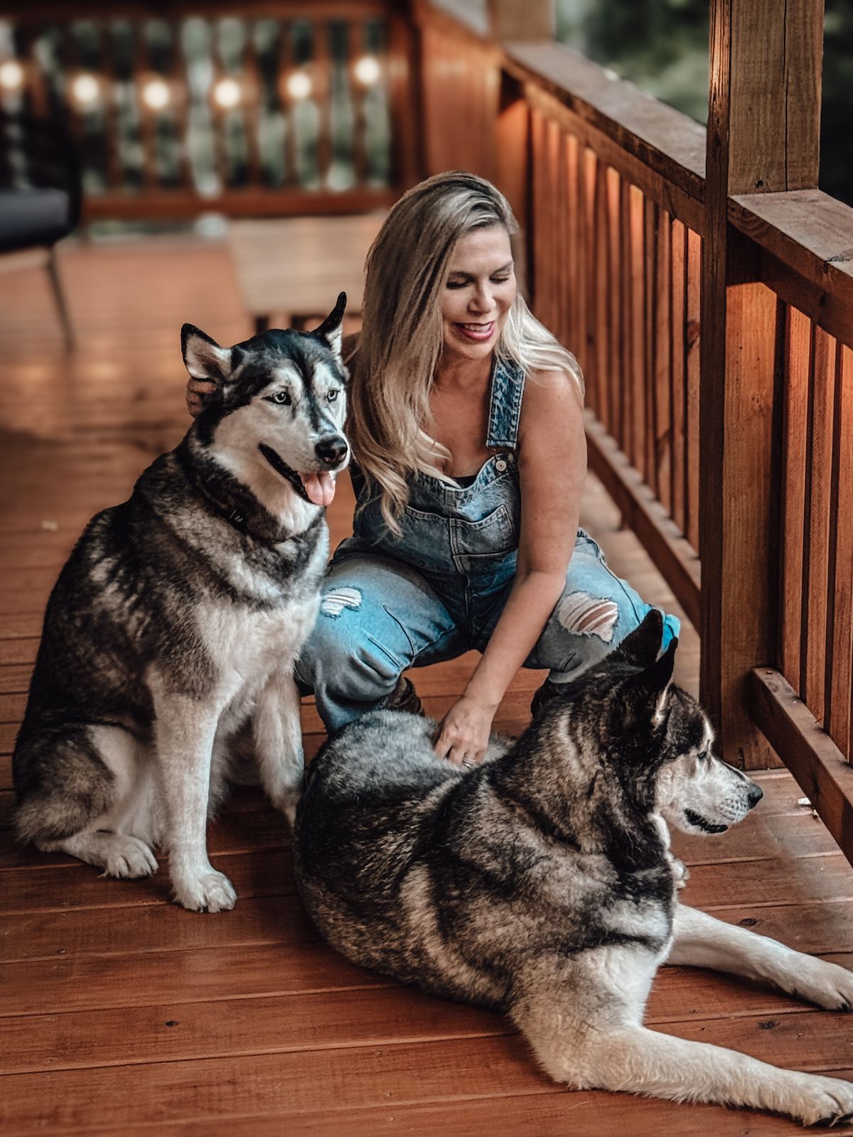 Tracy kneeling on a cabin deck with Luka and Sosa